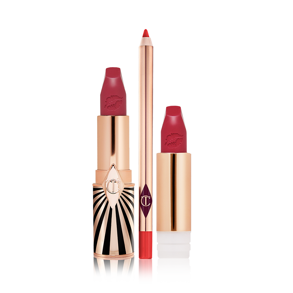 Lipstick in a dark, berry-pink shade with its refill next to it, both with lids removed, and a lip liner pencil in a bold, orange-red colour.