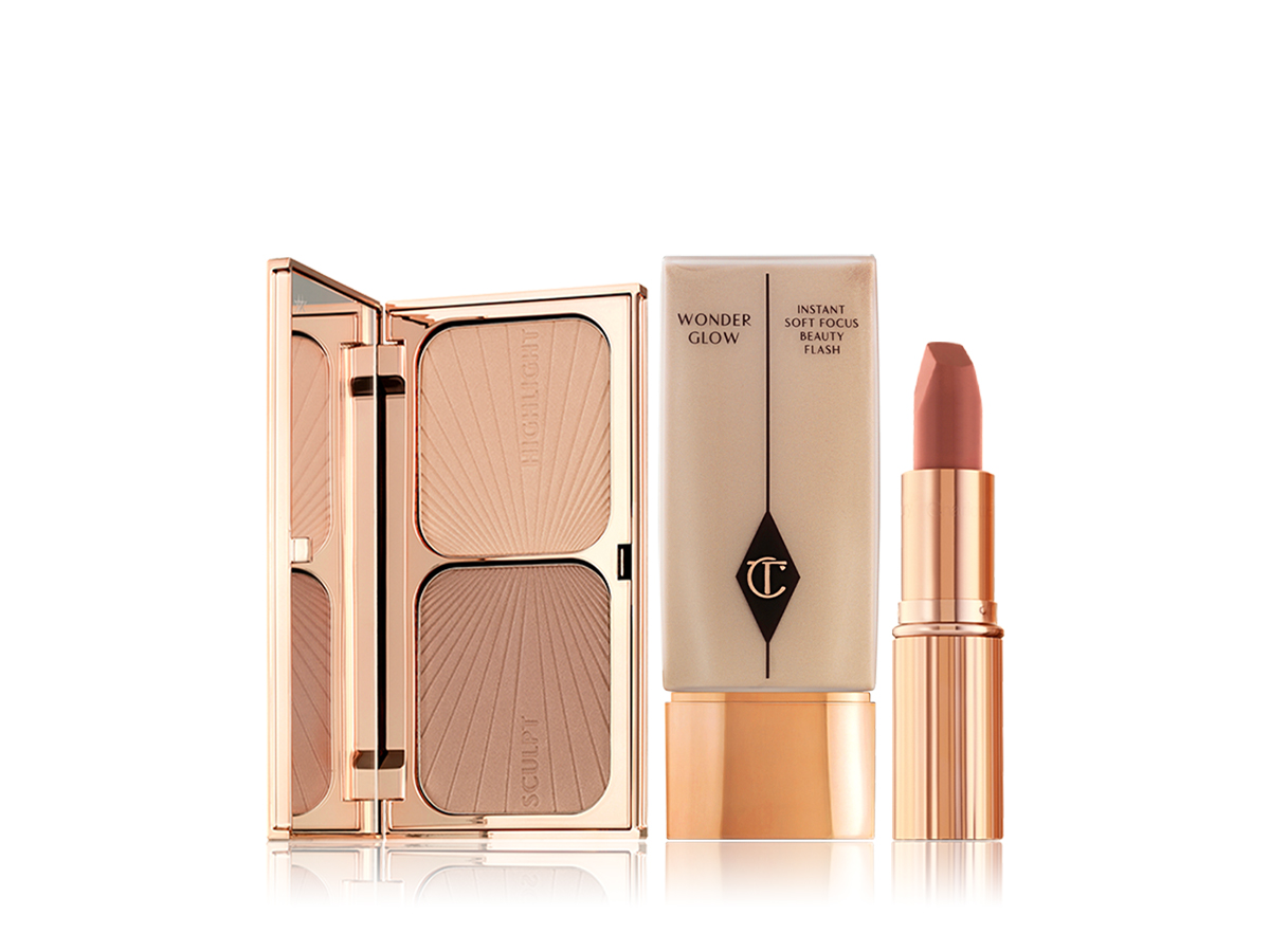 An open, mirrored-lid duo contour palette with a foundation bottle in a light beige shade, and a matte lipstick in a berry-pink shade in a gold-coloured tube.