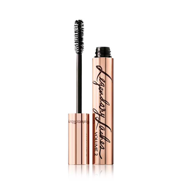 An open, black mascara in reflective, golden-coloured packaging with its applicator next to it. 