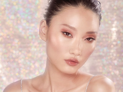 A fair-tone brunette model with brown eyes wearing dewy, luminous, nude-pink makeup. 