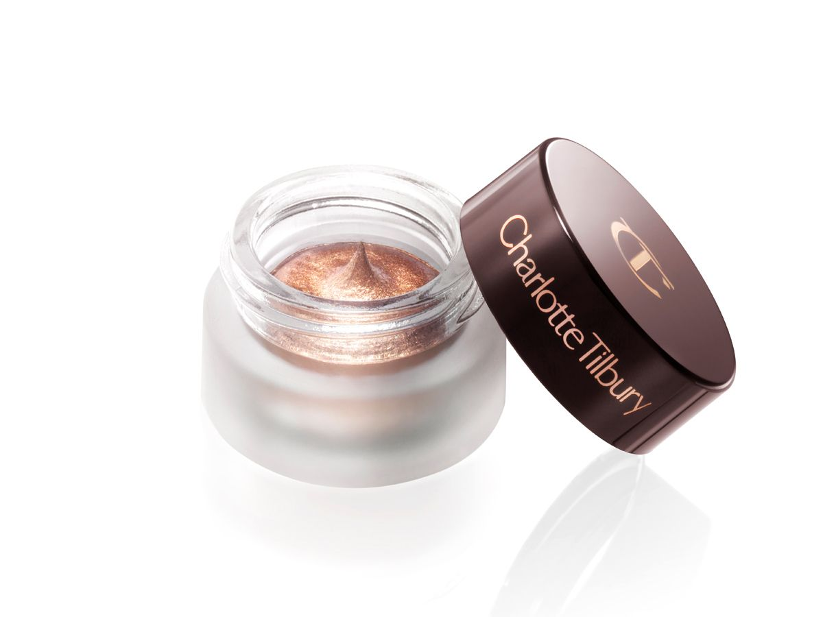 An open pot of cream eyeshadow in an antique oyster-gold shade with the lid next to it. 