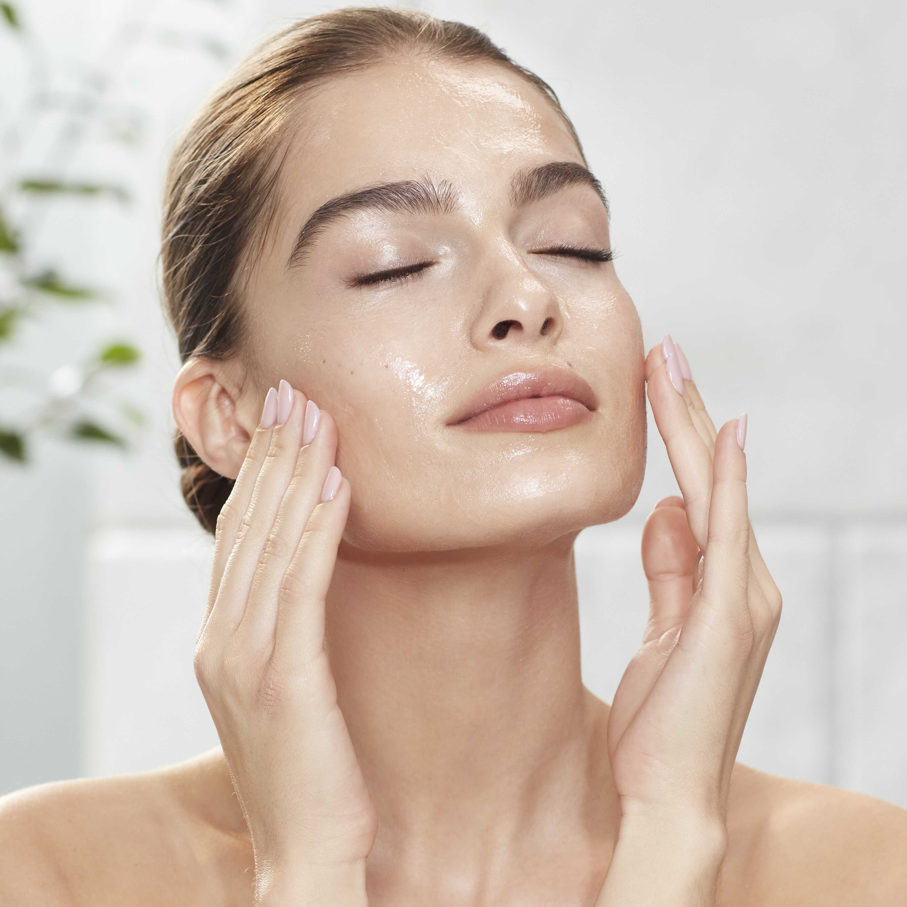 Light-tone model with smooth, flawless, and glowy glass skin applying a wash-off exfoliating mask.