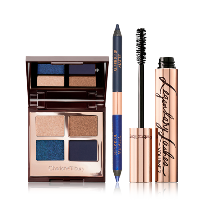 Open, quad eyeshadow palette with eyeshadows in shades of blue and golden with an open, double-ended blue eyeliner, and a black mascara in a golden tube with its applicator next to it. 