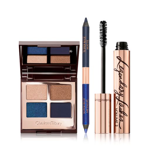Open, quad eyeshadow palette with eyeshadows in shades of blue and golden with an open, double-ended blue eyeliner, and a black mascara in a golden tube with its applicator next to it. 