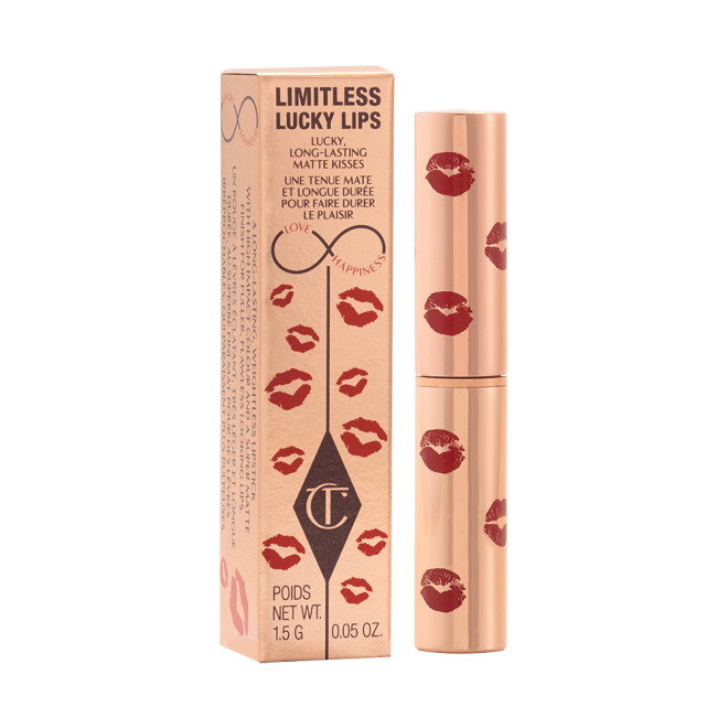 A closed lipstick tube in gold colour with red-coloured kiss print all over the lipstick tube next to its gold-coloured packaging box with similar kiss prints on that. 