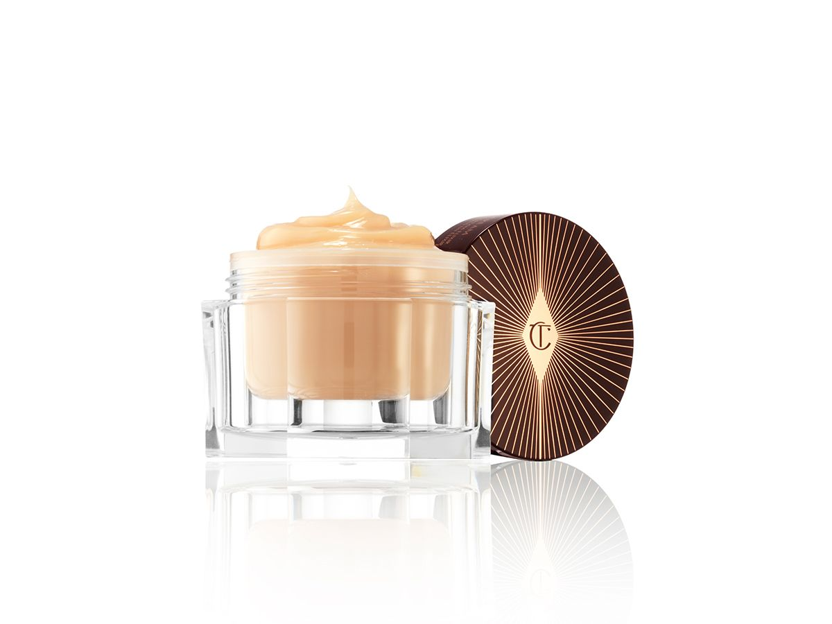 A thick, champagne-coloured night cream in a glass jar with its lid next to it. 
