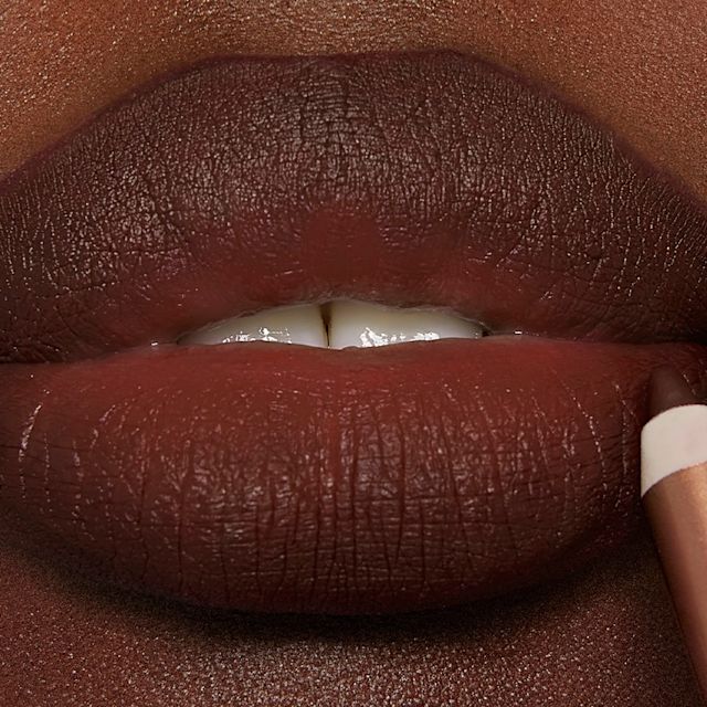 Model wearing Pillow Talk Intense Lip Cheat deep brown-pink lip liner