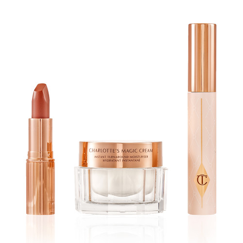 Pearly-white face cream in a glass jar with a gold-coloured lid, black mascara in a pink tube with a gold-coloured lid, and golden-peach matte lipstick in a gold-coloured tube.