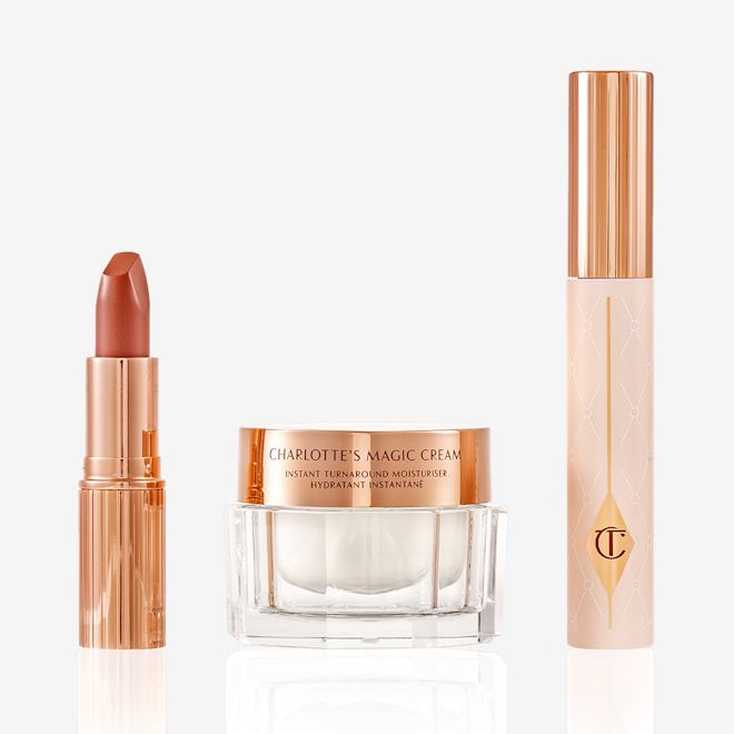 Charlotte Tilbury's Magic Icons kit displayed Pearly-white face cream in a glass jar with a gold-coloured lid, black mascara in a pink tube with a gold-coloured lid, and golden-peach matte lipstick in a gold-coloured tube.