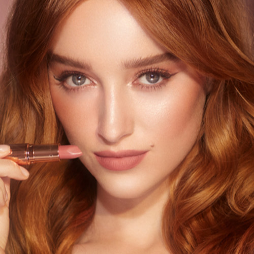 Fair-tone model with blue eyes wearing glowy, nude pink blush with black-coloured eyeliner and a nude pink lipstick with a matte finish.