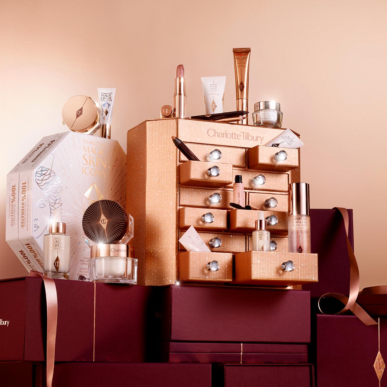 A golden-coloured chest of drawers with a clay mask, nude pink matte lipstick, nude pink lip liner, eyeliner pencil in dark copper, black-coloured mascara, liquid primer, champagne-coloured liquid highlighter, dark brown eyeliner pencil, pearly-white face cream, luminous ivory-coloured serum, and bronze-coloured body highlighter. 