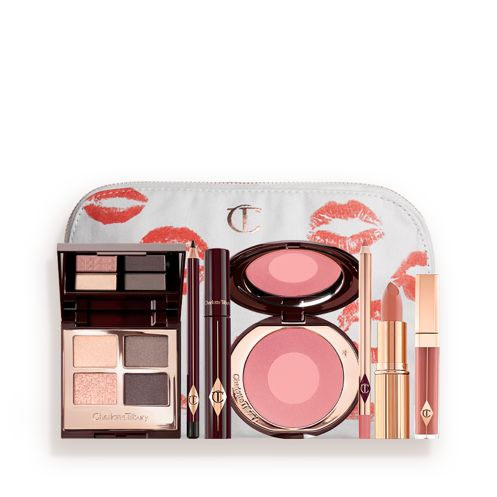 A makeup bag with 7 makeup products, which are a quad eyeshadow palette in shades of champagne, greys and pink, dark brown eyeliner pencil,  mascara, a two-tone pearlescent pink powder blush, nude pink liner, a peach-toned nude lipstick, and a soft pink lip gloss. 