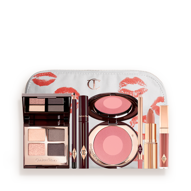 The Uptown Girl Makeup Kit & Complimentary Makeup Bag displayed A makeup bag with 7 makeup products, which are a quad eyeshadow palette in shades of champagne, greys and pink, dark brown eyeliner pencil, mascara, a two-tone pearlescent pink powder blush, nude pink liner, a peach-toned nude lipstick, and a soft pink lip gloss.