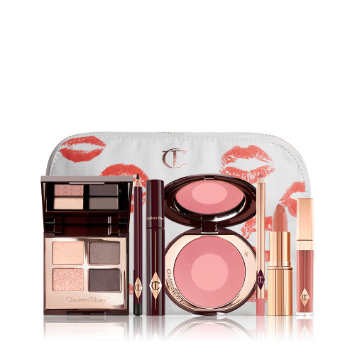 A makeup bag with 7 makeup products, which are a quad eyeshadow palette in shades of champagne, greys and pink, dark brown eyeliner pencil,  mascara, a two-tone pearlescent pink powder blush, nude pink liner, a peach-toned nude lipstick, and a soft pink lip gloss. 
