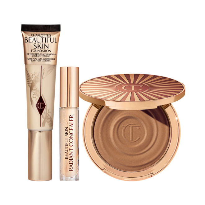 Foundation in a sleek gold-coloured tube with a concealer in a glass tube and gold-coloured lid, and dark brown cream bronzer compact in gold-coloured packaging.