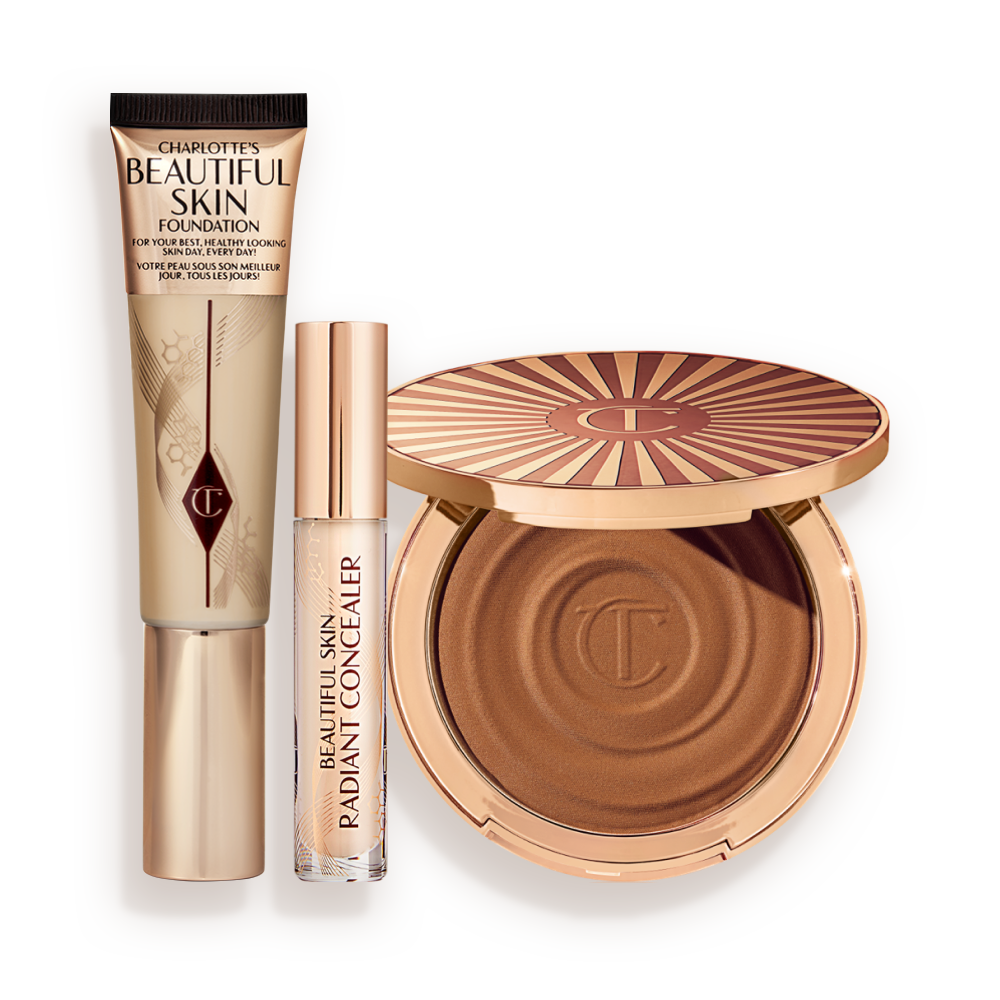 Foundation in a sleek gold-coloured tube with a concealer in a glass tube and gold-coloured lid, and dark brown cream bronzer compact in gold-coloured packaging.