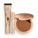 Foundation in a sleek gold-coloured tube with a concealer in a glass tube and gold-coloured lid, and dark brown cream bronzer compact in gold-coloured packaging.