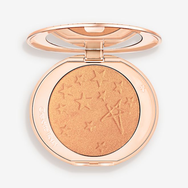 Hollywood Highlighter Gilded Glow open An open highlighter powder compact in a true gold shade with a mirrored lid.