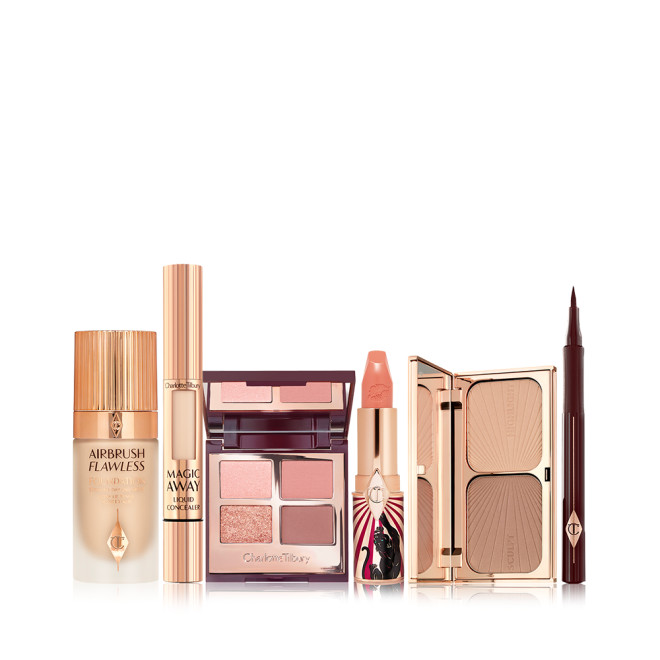 Foundation in a glass bottle with gold-coloured lid, open mirrored-lid quad eyeshadow palette with an open, nude peach lipstick in a funky tube with a panther on it, duo contour palette with a mirrored-lid, liquid concealer, and eyeliner pen in dark brown. 