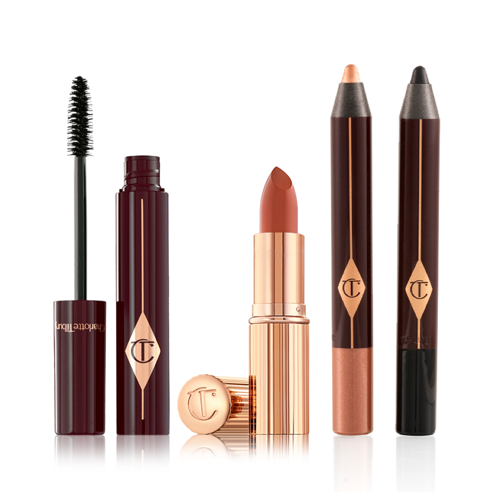 Black mascara in an open plum-coloured tube with its applicator next to it, an open coral lipstick in a gold-coloured tube, chubby eyeshadow stick in rose gold, and chubby eyeshadow stick in black.