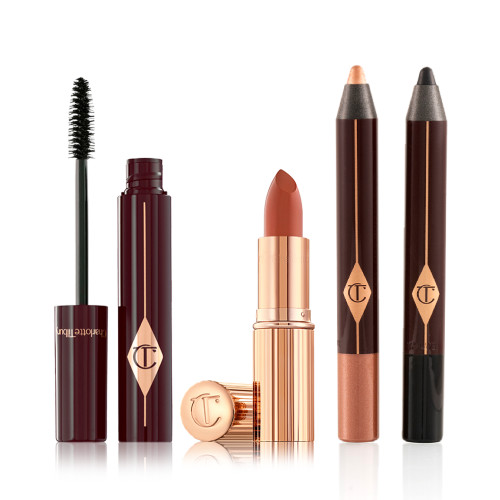 Black mascara in an open plum-coloured tube with its applicator next to it, an open coral lipstick in a gold-coloured tube, chubby eyeshadow stick in rose gold, and chubby eyeshadow stick in black.