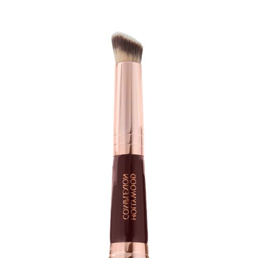 Close-up of a concealer brush with fawn and dark brown bristles with a rose-gold and dark crimson handle. 