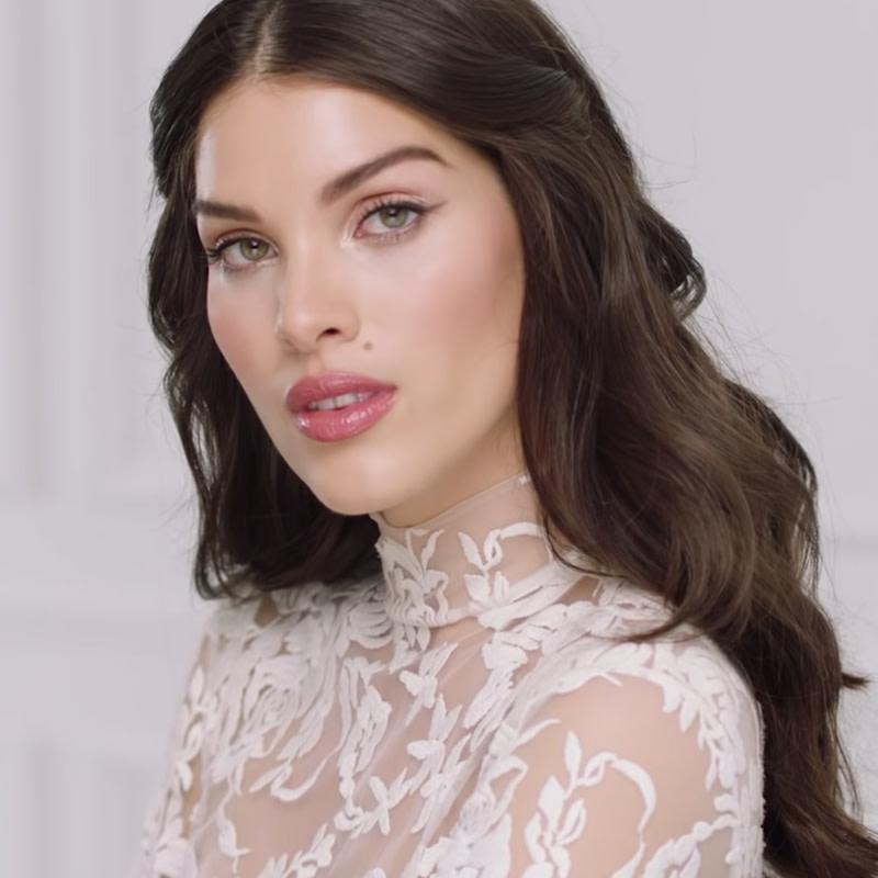 A fair-tone brunette bride with a flawless, glowy base wearing glossy bright pink lipstick with muted, nude pink makeup. 