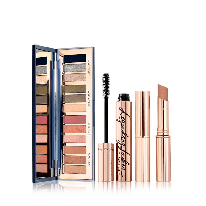 An open, mirrored-lid eyeshadow palette in twelve shimmery and matte eyeshadows in smokey grey, pink, and brown shades, an open mascara in golden packaging with its applicator next to it, and an open terracotta-brown, sparkly lipstick. 