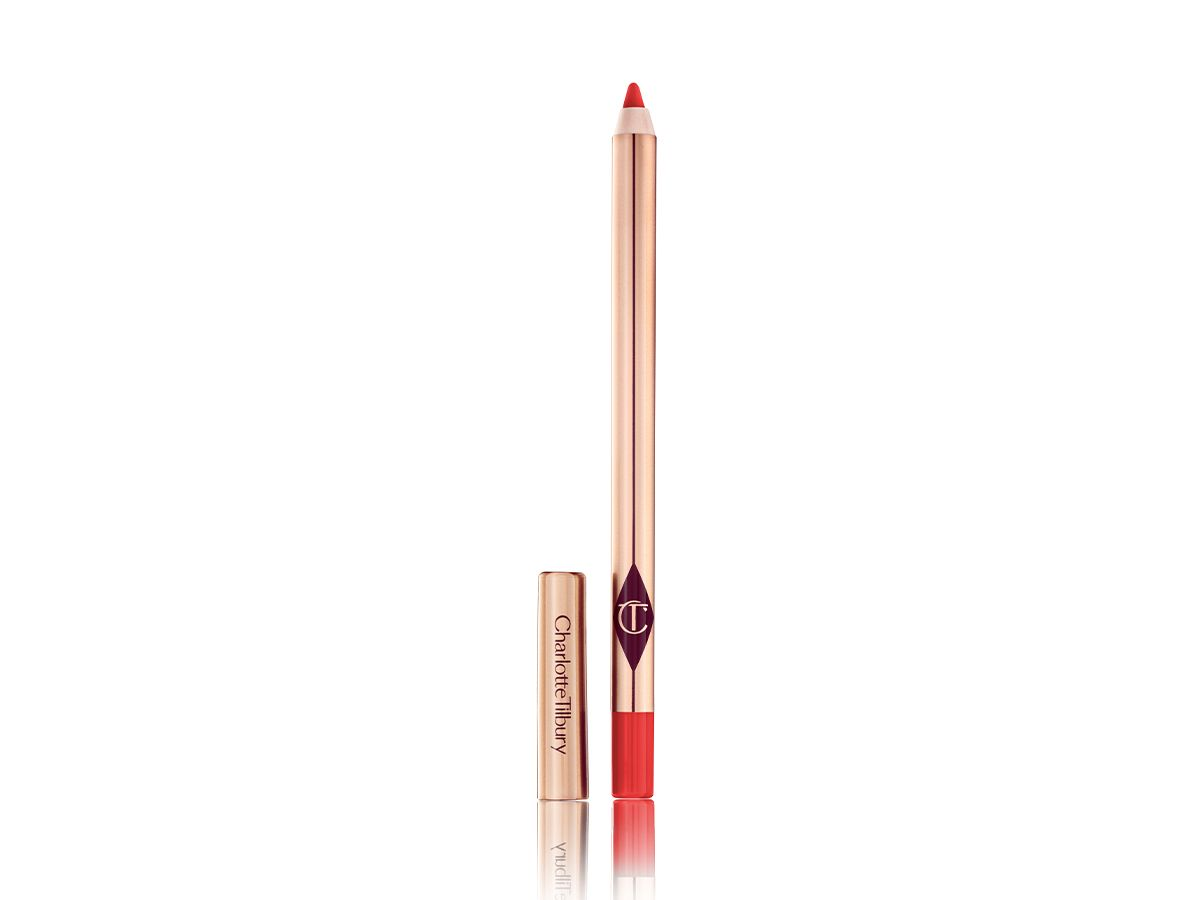 A lip liner pencil in a bright orange-red shade with its lid next to it. 