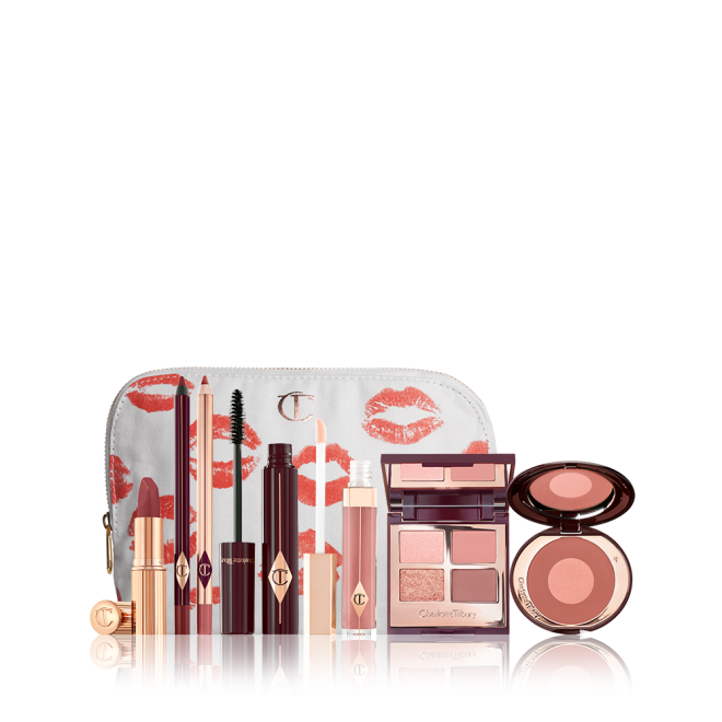 A white makeup pouch with open makeup products that are a berry-rose lipstick, maroon eyeliner pen, a rose-pink lip liner pencil, mascara, nude-pink lip gloss, a quad eyeshadow palette in earthy tones, and a two-tone blush in warm pink. 