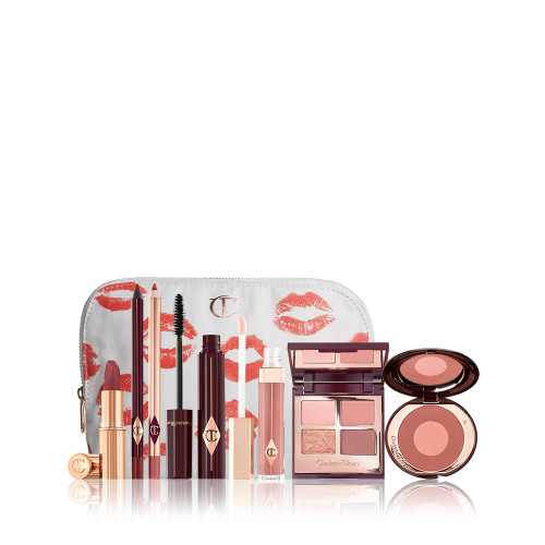 A white makeup pouch with open makeup products that are a berry-rose lipstick, maroon eyeliner pen, a rose-pink lip liner pencil, mascara, nude-pink lip gloss, a quad eyeshadow palette in earthy tones, and a two-tone blush in warm pink. 