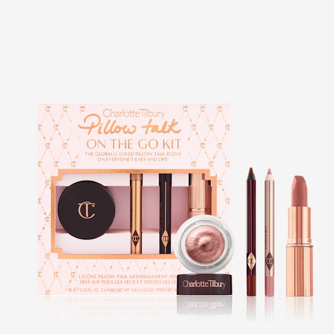 PILLOW TALK KIT à emporter PAQUET An unpacked makeup kit that includes a nude pink matte lipstick, nude pink lip liner pencil, warm berry eyeliner pencil, and rose gold cream eyeshadow in a petite glass pot, with a pink-coloured packaging gift box behind the products.
