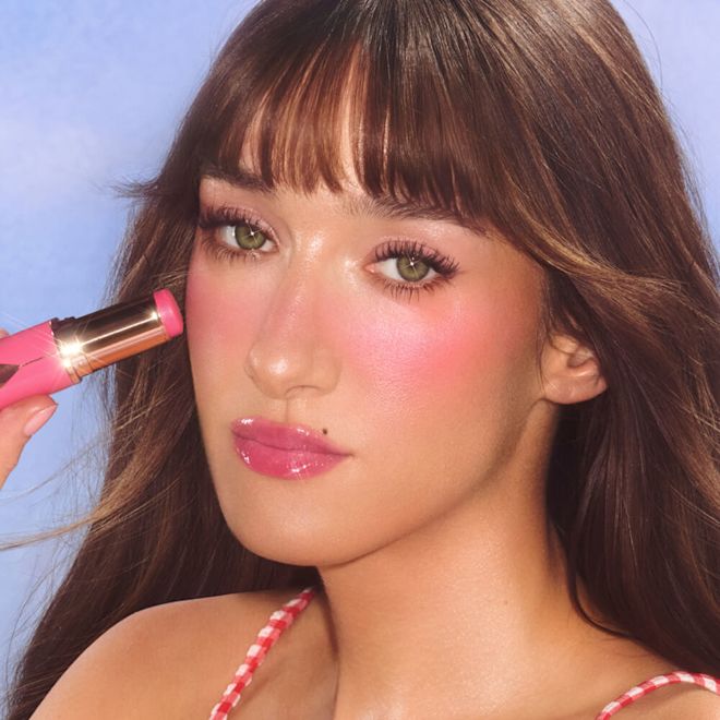 Medium model wearing and holding pink blush shade.