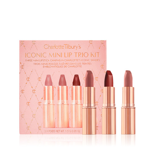 Three mini lipsticks in different shades of nude in gold-coloured tubes with a pink-coloured makeup box.