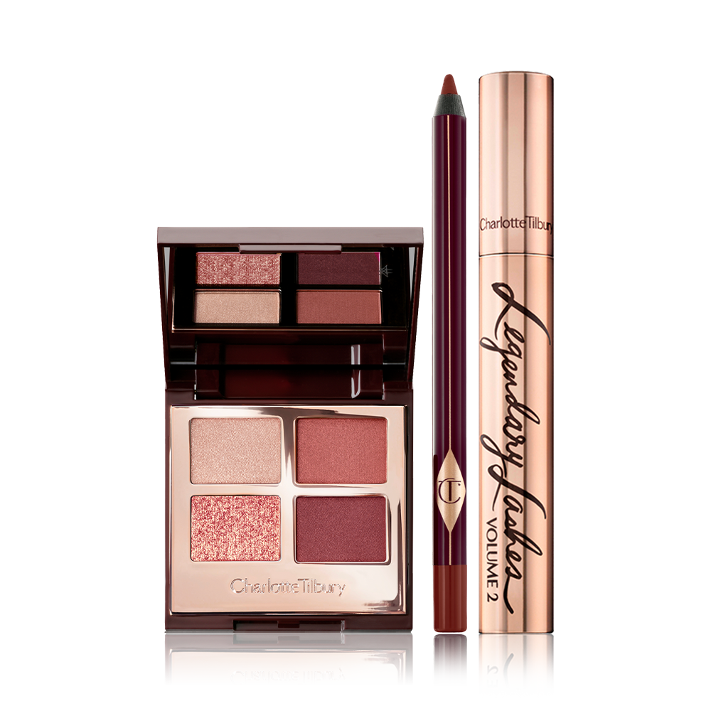 An open, quad eyeshadow palette with shades of cranberry and gold  with a berry-brown eyeliner pen, and black mascara in gold packaging.