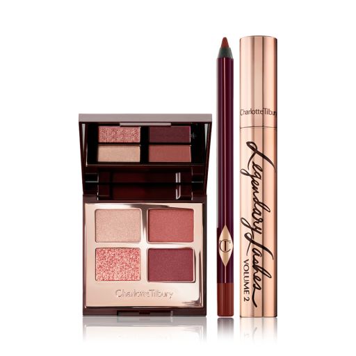 An open, quad eyeshadow palette with shades of cranberry and gold  with a berry-brown eyeliner pen, and black mascara in gold packaging.