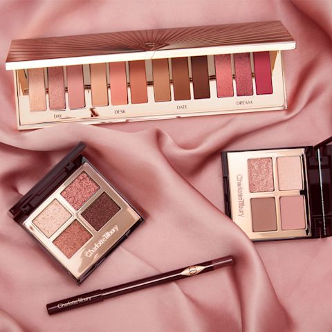 Three, open eyeshadow palettes in neutral colours that include matte and shimmery pink, brown, gold, and peach along with an eyeshadow blending brush. 