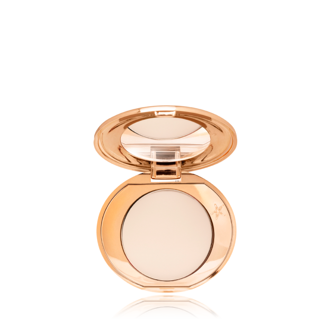 An open, mirrored-lid, mini, pressed powder compact in a cream colour. 