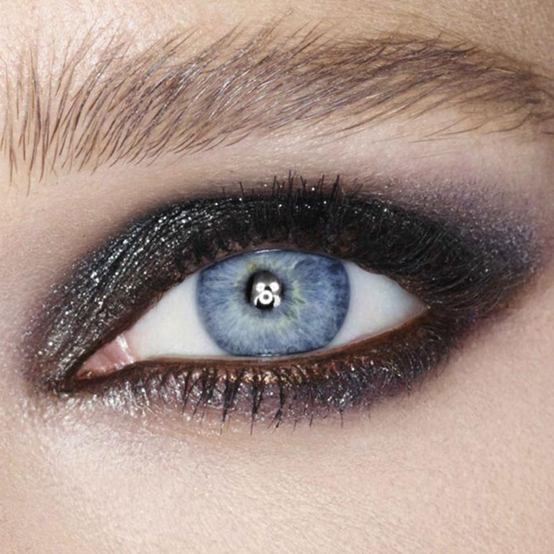 Eye close-up of a model with blue eyes wearing glittering black eyeshadow. 