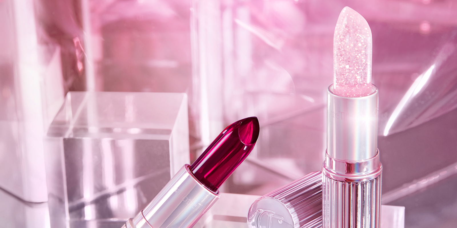 Two, open, colour-changing lipsticks in lilac-coloured tubes in a glowy red shade and glitter sheer pink shade. 