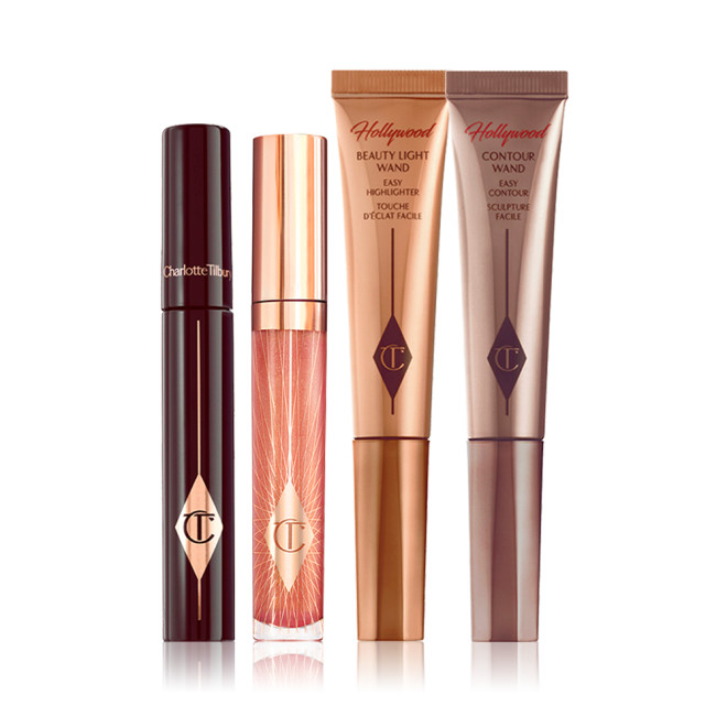 A mascara with a nude pink lip gloss and two highlighter wands in light gold and bronze-coloured packaging. 