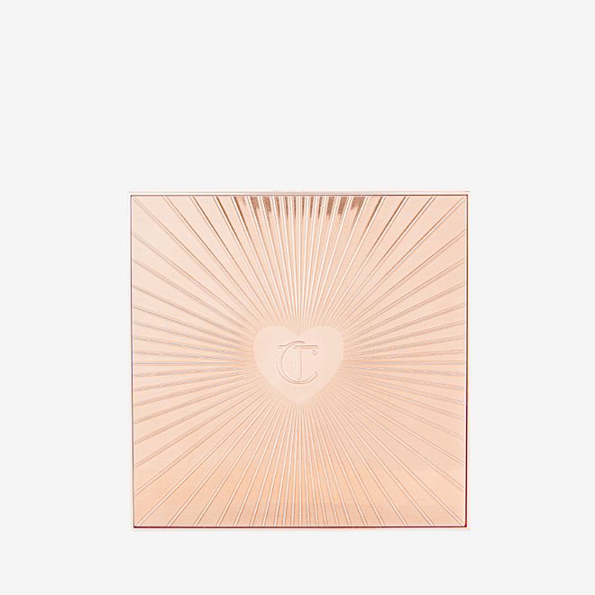 Instant Look in a Palette in Glowing Beauty A closed, face palette with a rose-gold-coloured lid with a starburst pattern on top along with the CT logo embossed in the middle.