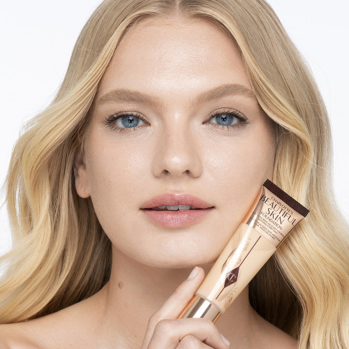 Light-tone blonde model wearing glowy, skin-like foundation with a satin finish with nude lipstick and subtle eye makeup.