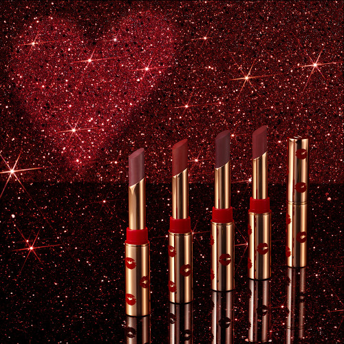 A collection of five, open, 5 universally-flattering red-toned lipsticks with a matte finish, in gold-coloured tubes with a playful, kiss-print pattern. 