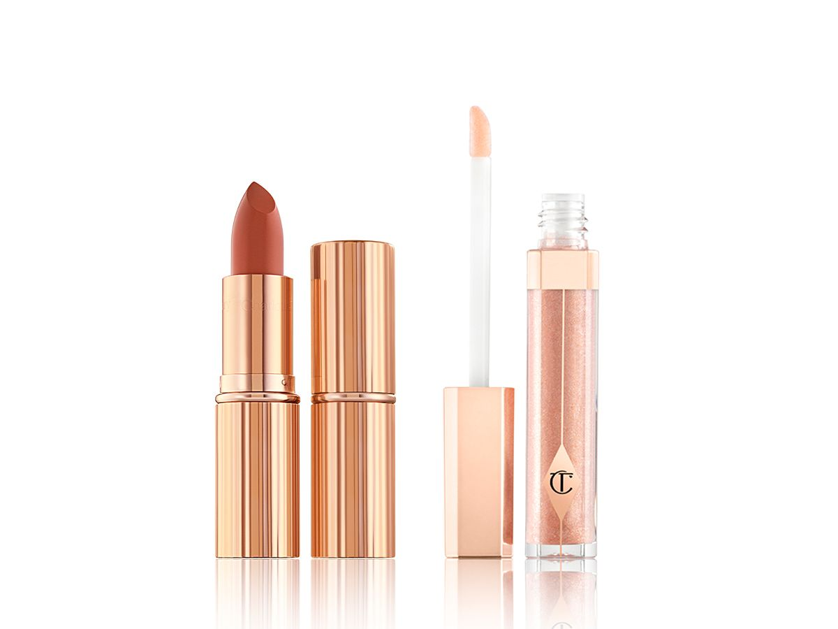 Two lipsticks, with and without lid in a dark peach shade with a nude peach lip gloss with its doe-foot applicator next to it. 