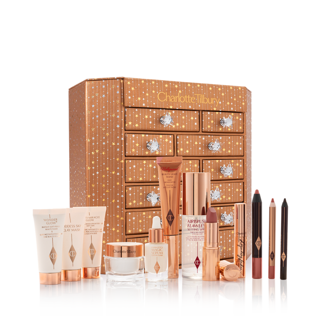 A golden-coloured chest with twelve drawers with shiny, silver-coloured star handles with the products inside displayed, hich include makeup primers, clay mask, face cream, liquid highlighter wand, setting spray, lipstick. mascara, chubby eyeshadow stick, lip liner pencil, and eyeliner.