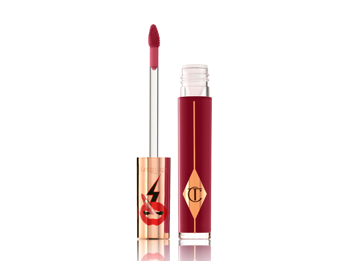 A crimson-red lip gloss in a clear glass tube with its doe-foot applicator next to it. 