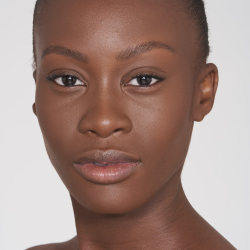 A deep-tone brunette model wearing nude pink makeup along with a pressed powder in dark brown colour that makes her skin looks matte and flawless. 