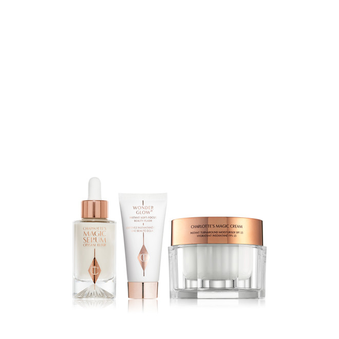 Luminous pearly-coloured serum in a glass bottle with a white and gold-coloured dropper lid, primer in a white tube with a gold-coloured lid, and pearly-white face cream in a glass jar with a gold-coloured lid.