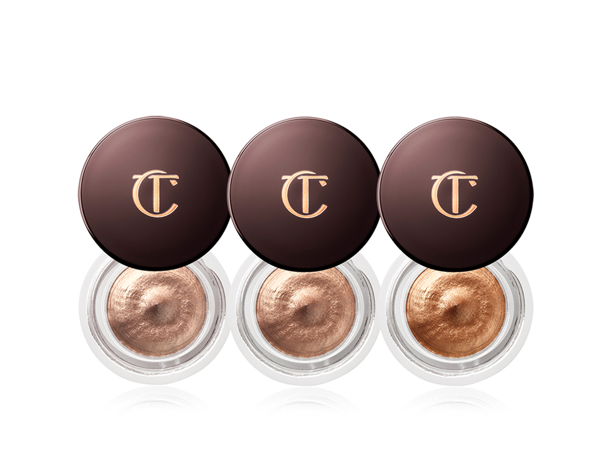 Three open cream eyeshadows trio in shades of gold and brown in glass pots with dark crimson lids with the CT logo printed on them.